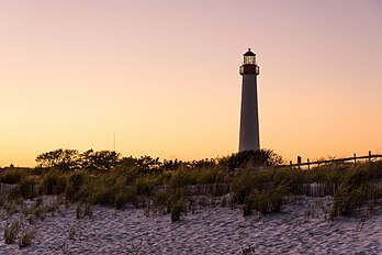 Farol de Cape May, Cape May, Nova Jersey, ao pôr do sol. O farol foi construído em 1859, automatizado em 1946 e incluído no Registro Nacional de Lugares Históricos em 12 de novembro de 1973. O farol é o terceiro totalmente documentado a ser construído em Cape May Point. O primeiro foi construído em 1823 e o segundo em 1847. As localizações exatas dos dois primeiros faróis estão agora submersas devido à erosão. (definição 5 700 × 3 800)