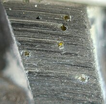 Un tros de metall polit amb diamants petits incrustast