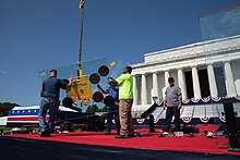 Photograph of several workers installing a plexiglass barrier