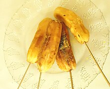 Four grilled bananas on wooden sticks