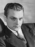 Черно-белое рекламное фото Джеймса Кэгни - белого мужчины с серьезными чертами лица, изогнутой бровью, темными глазами и зачесанными назад волосами, в костюме и примерно 30-летнего возраста - в начале 1930-х годов.