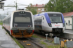 Norjalaisen (vas.) ja ruotsalaisen junayksikön matkustajat vaihtavat junia Östersundissa.