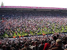 Photo des gradins d'une foule envahissant le terrain de football.