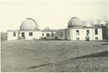 black and white image of a white building topped by two closed telescope domes