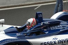 Photographie d'une voiture de sport-prototype bleu et blanche sur une piste, avec son pilote installé dans le cockpit.