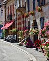 Devanture de débit de tabac avec son enseigne « Carotte », dans une perspective d'une rue fleurie et des reliefs de sa modénature, en France.