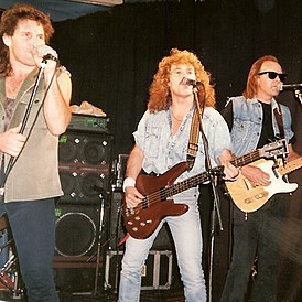 Ланкастер на сцене с Тайроном Коутсом (вокал) и Джоном Брюстером (гитара), участниками The Bombers