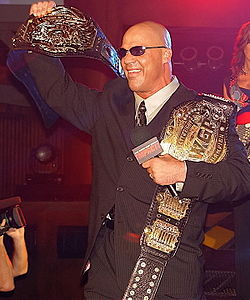 Kurt Angle พร้อมกับเข็มขัดแชมป์ TNA World Heavyweight Championship (ซ้าย) และเข็มขัดแชมป์ IWGP Heavyweight Championship (ขวา)