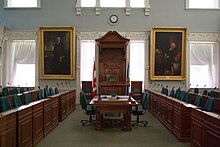 Parliamentary chambers with brown wooden benches and green chairs