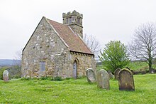 A small stone-built church, with a red pantiled roof, located in a graveyard