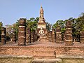 Grand wihan aux escaliers et sol en briques, aux colonnes en latérite avec en arrière-plan le chedi principal du temple sur un axe est-ouest