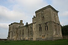 A stone building in a field, with a tower at each end.