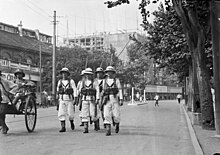 Dans une artère de Bombay en 1932, marins britanniques patrouillant en armes pour assurer l’ordre public.