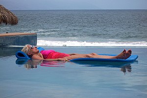 Mature lady sunbathing at swimming pool. Puert...