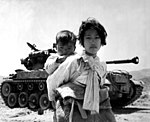 Une petit fille coréenne avec son petit-frère sur le dos pendant la Guerre de Corée.
