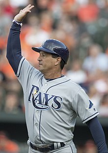 A man in a gray baseball uniform with navy undersleeves and cap