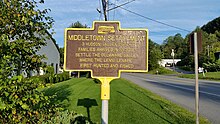 a picture of the historical marker which unlike other markers it has a brown background, not blue (but on both the letters are yellow)