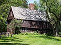 This brown colonial-style house has an overhanging second floor and a single central chimney.