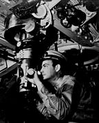 Officer at periscope in control room of a U.S. Navy submarine in World War II. The officer pictured is Captain Raymond W. Alexander, Sr. and the photo was taken in 1942.