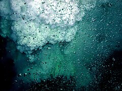 Bubbles of CO 2 in the foreground; droplets of liquid sulfur rise in the background