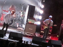Three members of rock band The Checks performing live at a rock concert