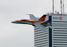 A CF-18 of the No. 409 Squadron flies by a BMO tower, 2011. CF-18 and BMO (6118847670).jpg