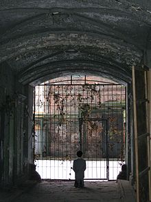 Him by Maurizio Cattelan (2001), depicting Adolf Hitler kneeling in prayer, exhibited in a courtyard in the former Warsaw Ghetto HIM byMaurizio Cattelan in Warsaw Ghetto 2013.JPG