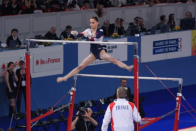 gymnast i split efter att roterat på dubbelbarr