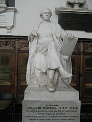 White marble statue of sitting man with crossed legs, holding a book