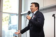 Yang holding a microphone while making a speech.