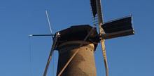 Photographie en couleurs d'une structure de bois et d'ardoise couronnant la tour d'un moulin.