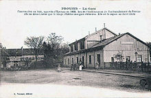 Carte postale de 1918. Quelques personnes devant le bâtiment de la gare à droite. Au centre une esplanade en terre battue.