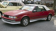 1989 Chevrolet Cavalier Z24 Convertible in Dark Red, front left (Hershey 2019).jpg