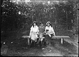 Bankje in het bos, met daarop een Duitse militair geflankeerd door twee vrouwen