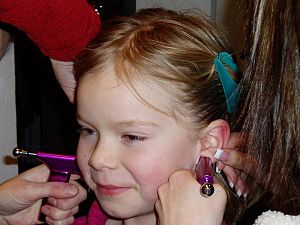 English: A little girl getting her ears pierced.
