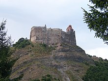 Photographie de ruines d'une forteresse sur une colline.