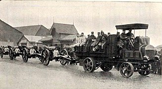 A battery of howitzers on the move. Note the gun crew members riding on the artillery tractor and seats on the gun carriage.