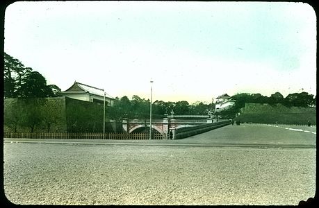 Road, sidewalk, pavement; stone walls and bridge, lamp standards; buildings and trees in background