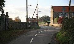 A colour image of a small road junction, with a row of houses