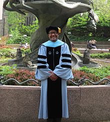 A Columbia Doctor of Education in doctoral regalia. The rules of academic dress in the United States were first standardized at Columbia, before spreading to Harvard and Yale. 2013 Columbia University Doctoral Robe.jpg