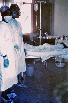 Медыцынскія сёстры каля ложку з хворым на ліхаманку Эбола