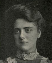 A young white woman with hair in a bouffant updo, wearing a high-collared dress with lace embellishments