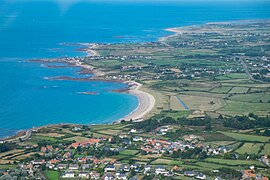 Vue aérienne d'un paysage plat, à gauche la mer qui pénètre sur les terres à droite en plusieurs petites anses séparées par de petites pointes rocheuses.