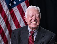Carter sitting in front of the U.S. flag