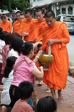 Sekelompok bhikkhu dan samanera melakukan pindapata (pengumpulan dana makanan) di Luang Prabang, Laos.