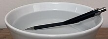 A pen partially submerged in a bowl of water appears bent due to refraction at the water surface. Pen in water.jpg