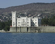 Photographie en couleurs représentant le château de Miramare de couleur claire et de style éclectique dominant la mer