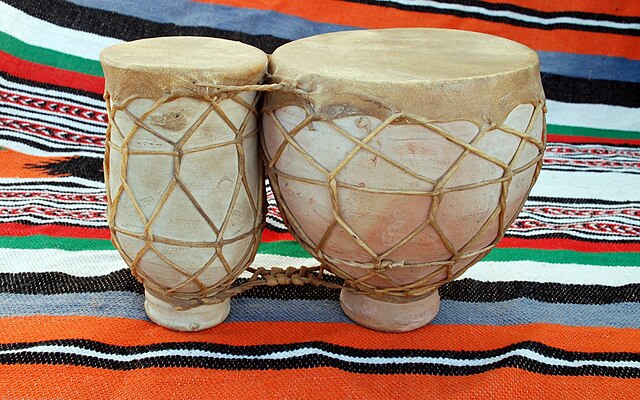 2 poteries fermées par des peaux, liées et cerclées par des lanières de cuir, posées sur une couverture marocaine.