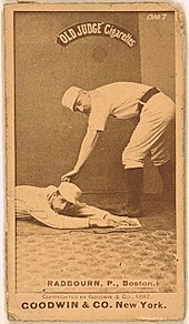 A picture depicting a baseball player who is holding a ball that tagging out another baseball player who attempting to reach base