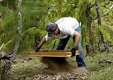 An archaeologist sifting for POW remains on Wake Island. Sifting for POW remains, Wake Island.jpg